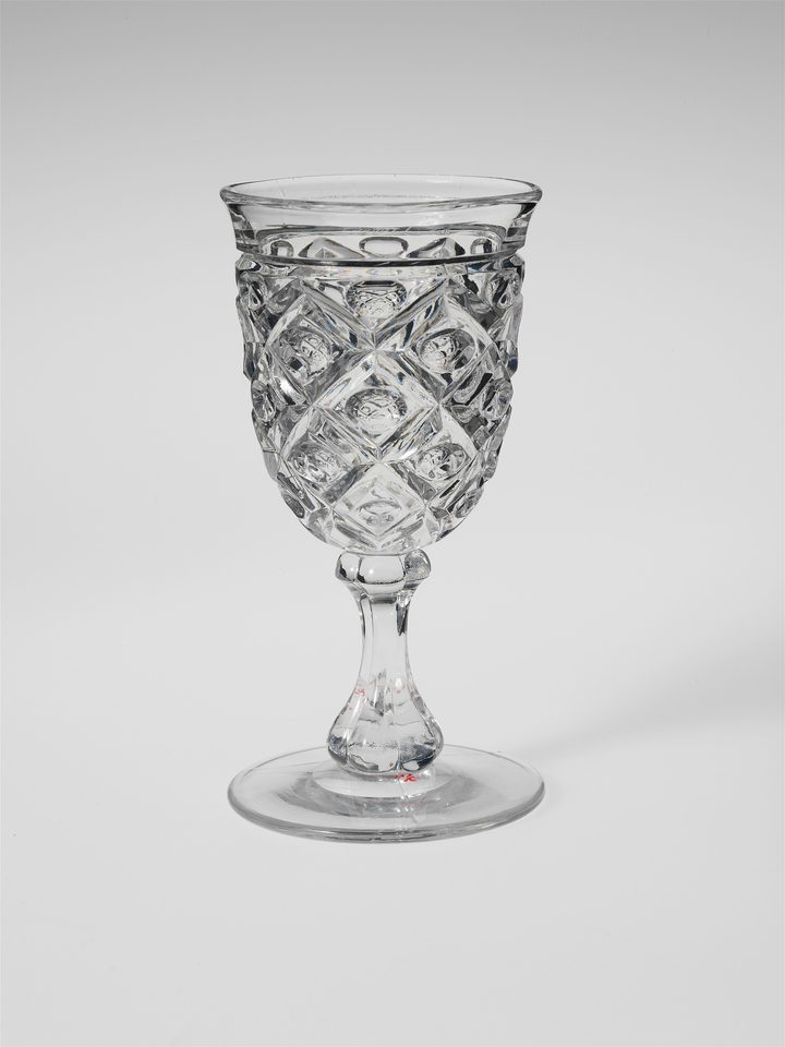 A cut-glass goblet in front of a grey backdrop